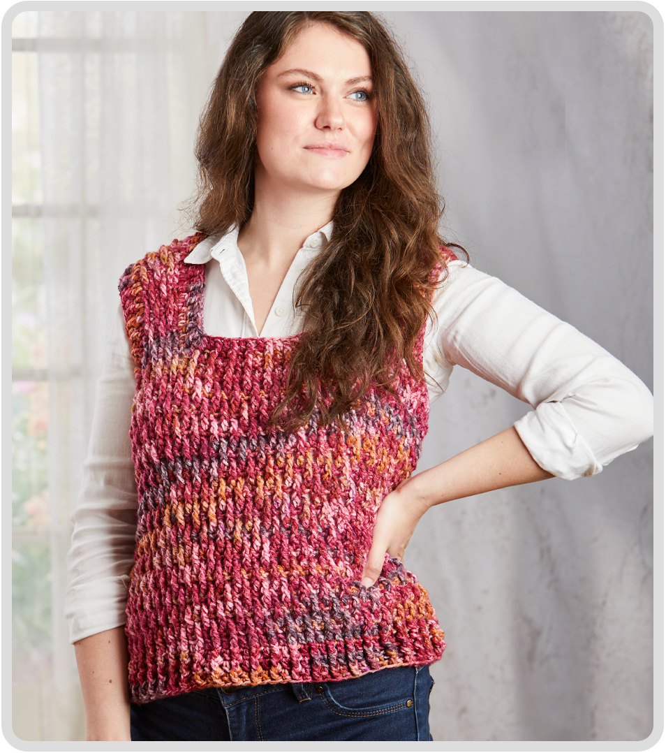 Woman wearing a colorful knitted Strata Vest crochet kit